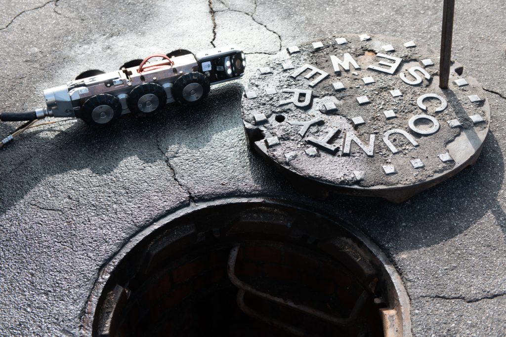 photo of an open manhole with a remote bot to scan sewer line